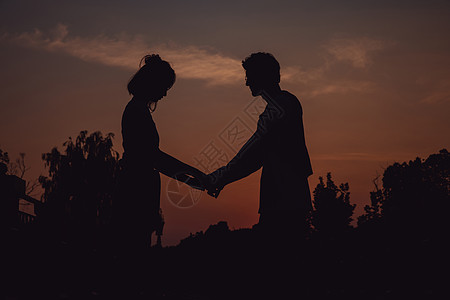 夕阳下手拉手的情侣剪影背景图片