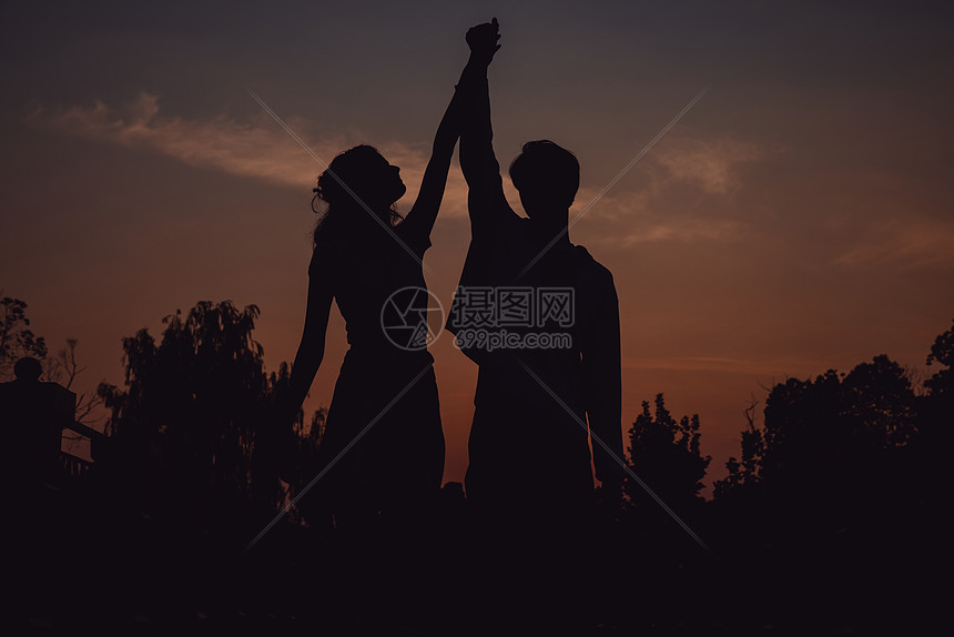 夕阳下牵着手舞蹈的情侣剪影图片