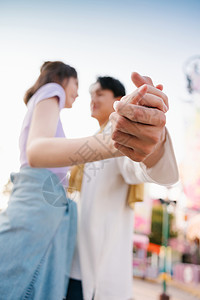 在游乐园牵着手的年轻情侣特写图片