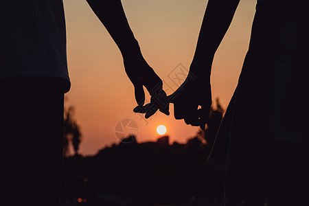 甜蜜夕阳下的情侣勾手指的剪影背景