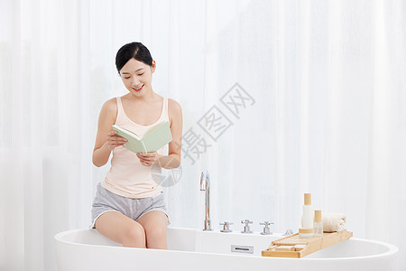 美女坐在浴缸前看书图片