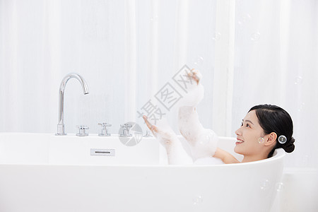 年轻女性躺在浴缸洗泡泡浴图片