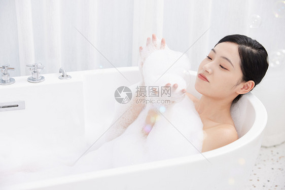 女性躺在浴缸洗泡泡浴玩泡泡图片