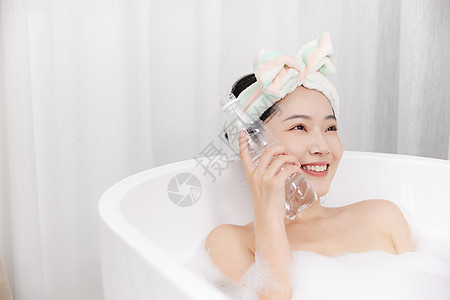 泡澡的青年女性拿水瓶降温图片