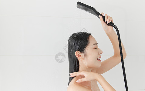 青年女性手拿花洒冲洗头发高清图片