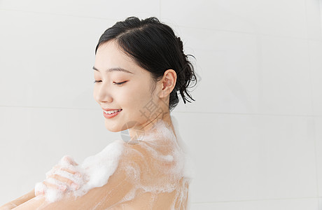 年轻女性使用沐浴球洗澡淋浴背景图片