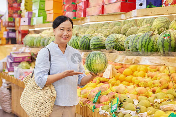 水果店内手拿西瓜展示的妇女图片