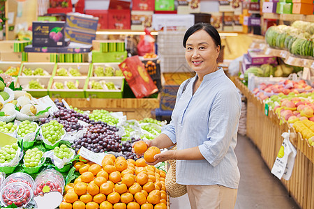 水果店内中年妇女挑选橘子图片