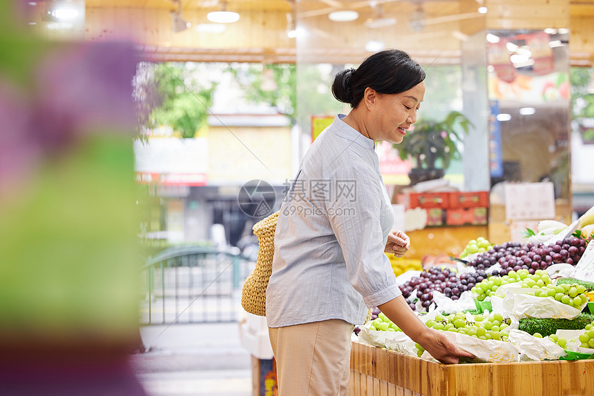 中年女性水果店内挑选水果图片