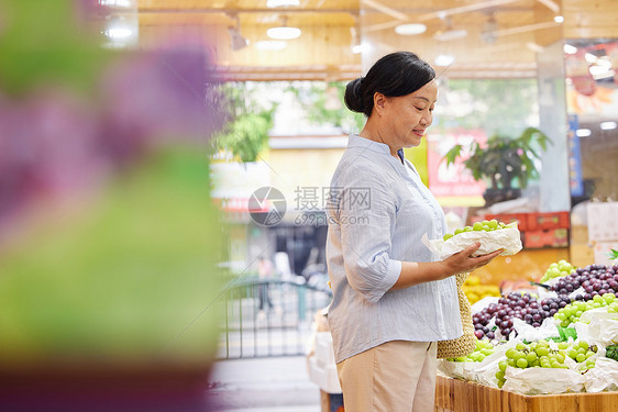 中年女性水果店内挑选水果图片