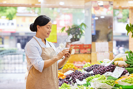 中年水果店店员手机记录水果数量图片