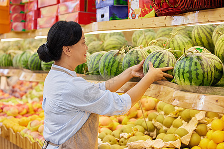 中年水果店店员整理西瓜背景图片