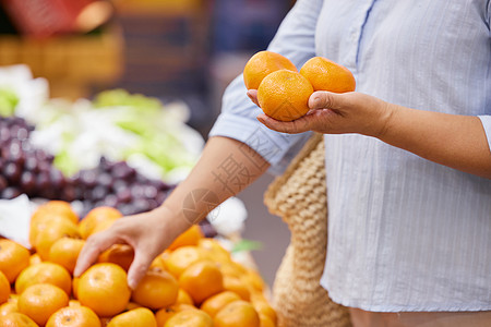 水果超市优惠券中年女性挑选橘子特写背景