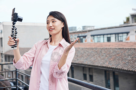 女视频博主拿相机户外拍摄背景图片