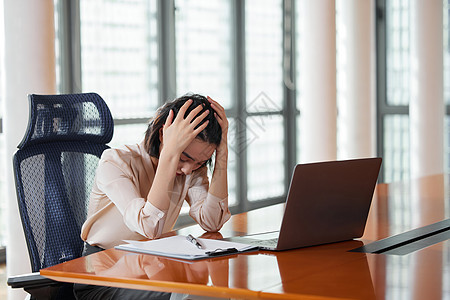 电脑前抱着头痛苦的职场女性高清图片
