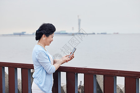 奶奶拿着手机对海边拍风景图片