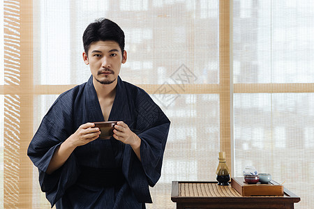 日系男性手拿茶杯喝茶背景图片