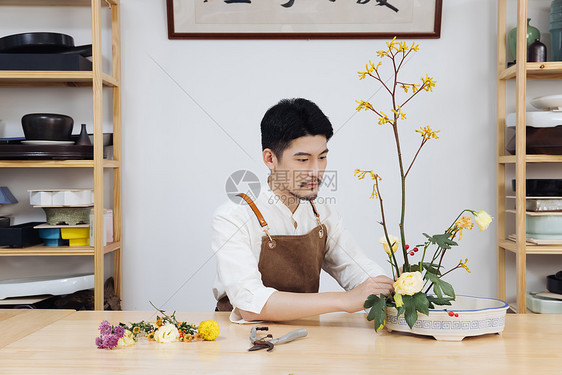 年轻男花艺师插花调整花枝图片