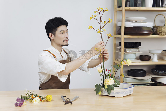 年轻男花艺师插花调整花枝图片
