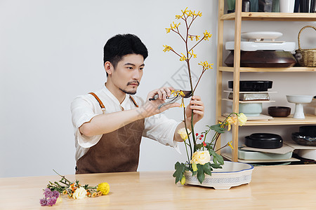 年轻男花艺师使用剪刀修剪花枝背景