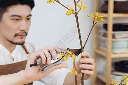 青年男性花艺师使用剪刀修剪花图片