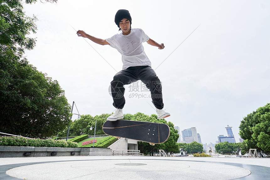青年男性户外玩滑板做动作图片