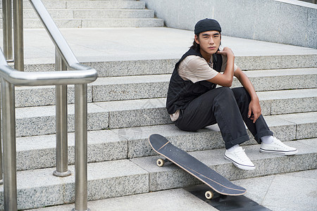 滑板男孩坐在台阶上休息高清图片
