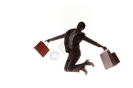双手拿着购物袋跳起来的女性剪影图片素材