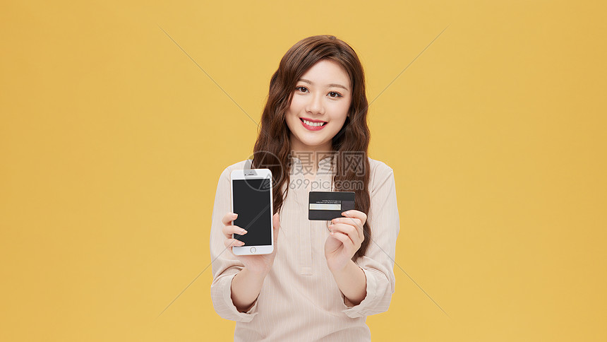 青年女性手拿信用卡和手机图片