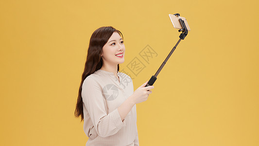 青年女性使用自拍杆手机直播图片
