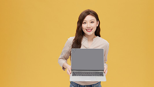 手拿电脑展示的年轻女性图片