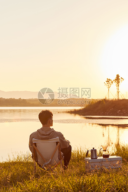 年轻男生坐在湖边看夕阳背影图片