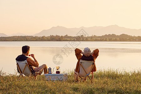 年轻情侣坐在湖边享受大自然图片