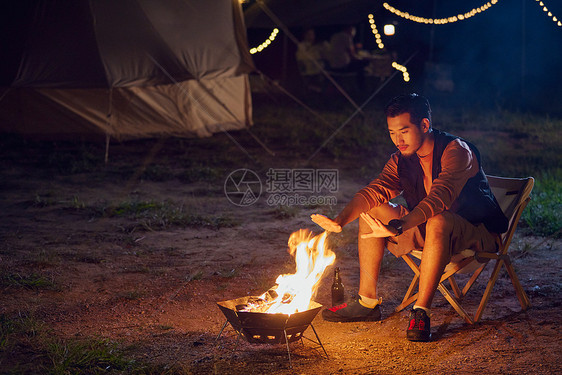 年轻男生户外野营烤火图片