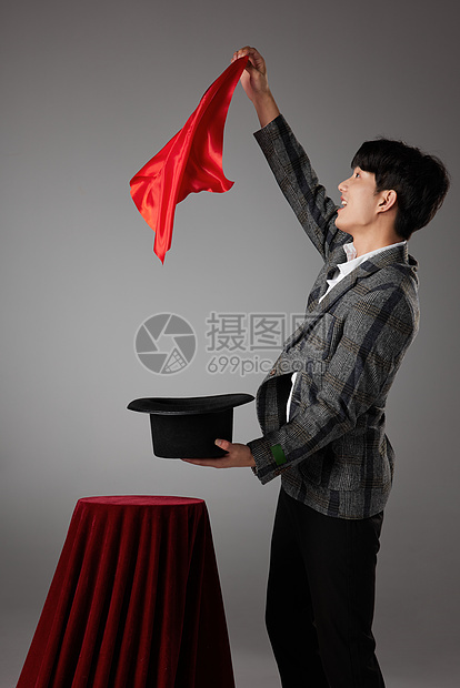 男性魔术师手拿红色方巾正在变魔术图片