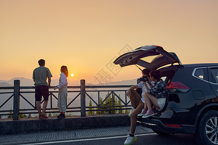 青年男女自驾旅行看夕阳背景图片