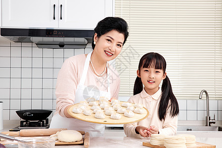 奶奶与孙女厨房里展示手工饺子图片