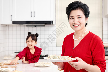 端着饺子的女人厨房里奶奶端着煮好的饺子背景