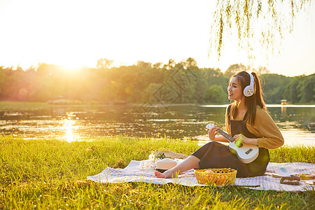 美女大学生野餐垫上听音乐弹琴图片