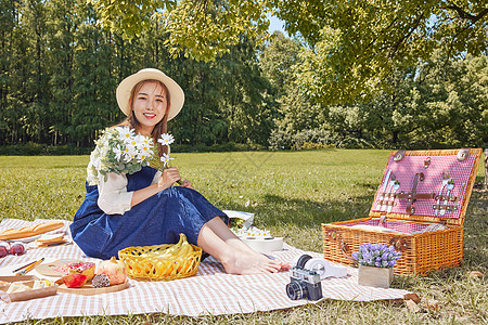 手捧食物篮美女户外草坪上手捧鲜花野餐郊游背景