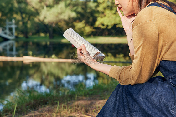 美女大学生公园湖边看书阅读特写图片