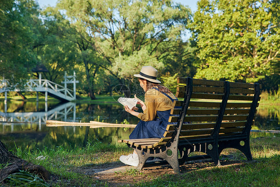 美女公园湖边长椅上看书阅读背影图片