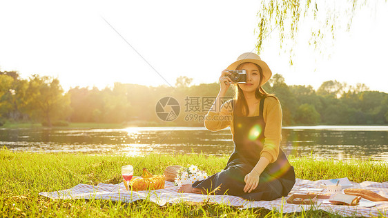 黄昏青年大学生郊游拿相机拍照图片