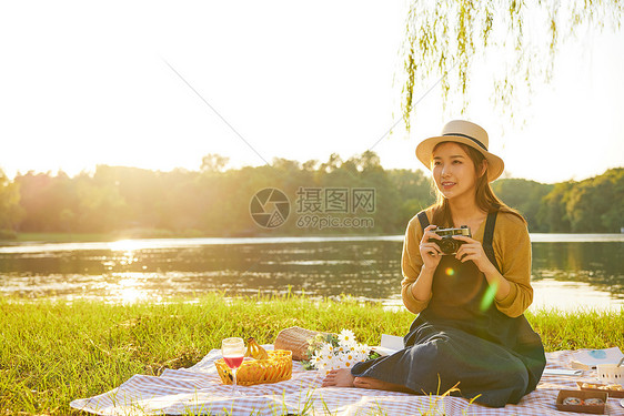 黄昏青年大学生郊游拿相机拍照图片