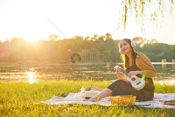 美女大学生野餐垫上听音乐弹琴图片