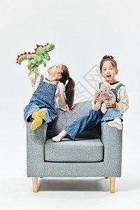 儿童双胞胎女孩坐沙发上搞怪嬉戏图片