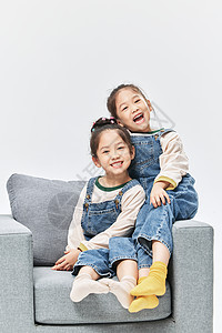 童年双胞胎小女孩沙发上亲密相伴图片