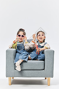 双胞胎小姐妹居家沙发上玩恐龙玩具图片