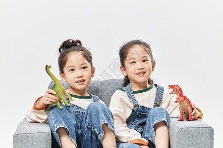 双胞胎小姐妹居家沙发上玩恐龙玩具图片