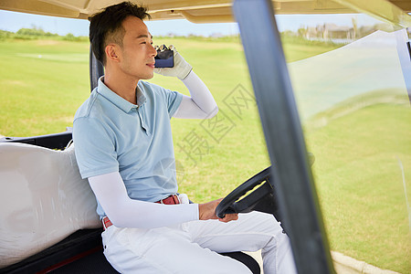 在高尔夫球车上打电话的男性图片